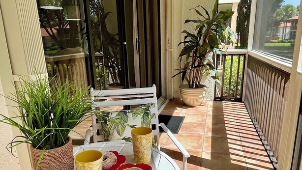 A covered outdoor seating area with a table, chairs, potted plants, and a ceiling fan. - 2 BEDROOM VILLA IN PARADISE...PGA NATIONAL...BEST PLACE TO BE! (Palm Beach Gardens)