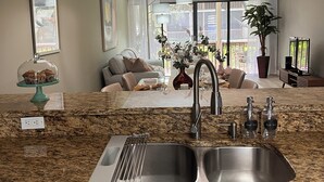 A kitchen with granite countertops, stainless steel sink, and wooden cabinets. - 2 BEDROOM VILLA IN PARADISE...PGA NATIONAL...BEST PLACE TO BE! (Palm Beach Gardens)