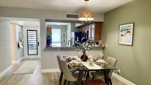 A dining area with a glass table, chairs, a vase with flowers, and a pendant light. - 2 BEDROOM VILLA IN PARADISE...PGA NATIONAL...BEST PLACE TO BE! (Palm Beach Gardens)