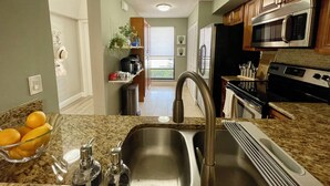 A kitchen with granite countertops, stainless steel appliances, and a view to the outside. - 2 BEDROOM VILLA IN PARADISE...PGA NATIONAL...BEST PLACE TO BE! (Palm Beach Gardens)