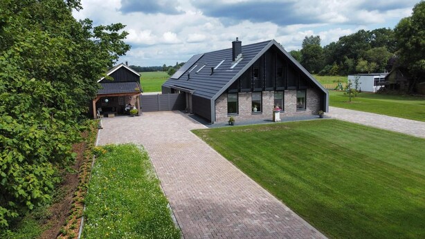 A modern farmhouse with a large barn, paved driveway, and well-maintained lawn.