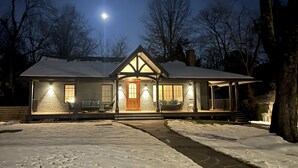 A snow-covered house with a front porch, a chimney, and a moon in the sky. - Mountain House in Town (Falls Church)