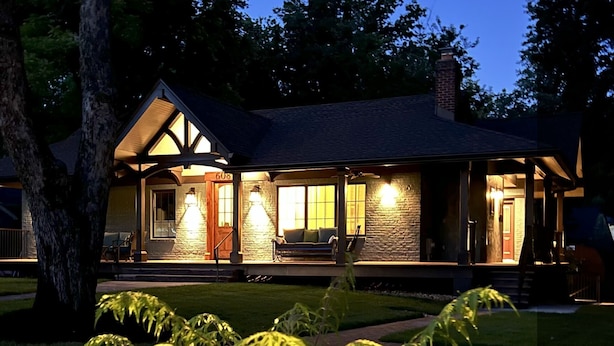 A two-story house with a stone facade, a front porch with seating, and a chimney. - Mountain House in Town (Falls Church)