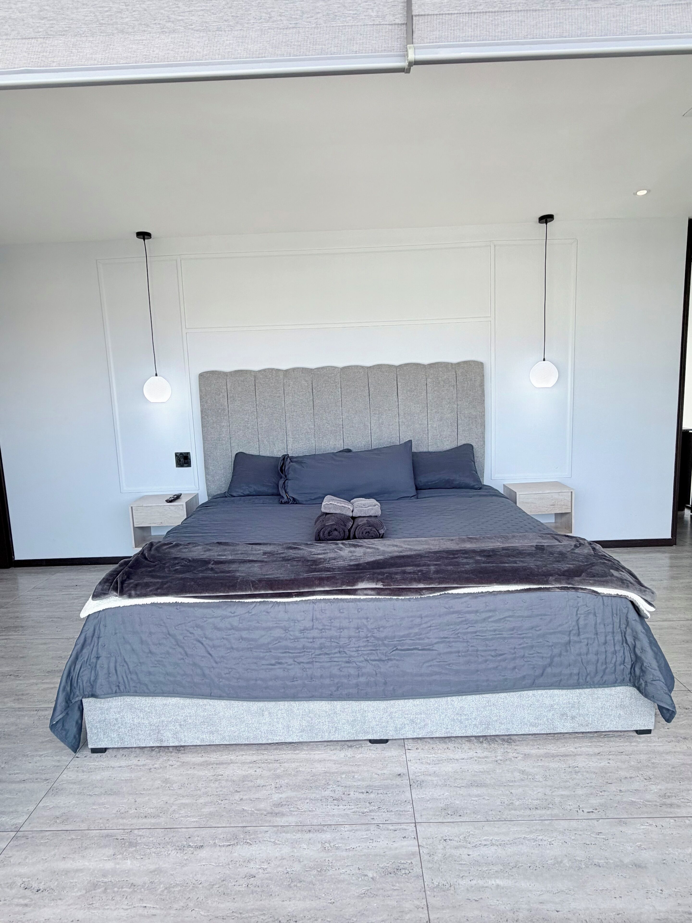 A modern bedroom with a large bed, two bedside tables, and a headboard.