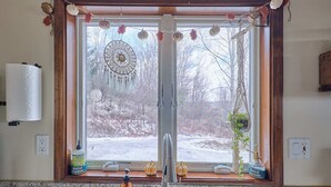Una cocina con ventana, grifo y dispensador de jabón.