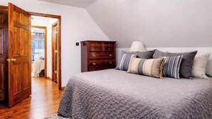 Un dormitorio con cama, cómoda de madera y puerta que da a un balcón.