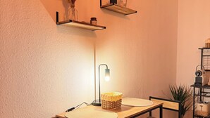 A small, cozy room with a desk, two chairs, a lamp, and shelves with decorative items. - Cozy studio near university & hospital by CASTORA HOMES (Kassel)