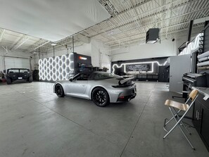 A spacious indoor garage with a silver sports car, a black SUV, and a hexagonal light installation. - Production Studio - 4 Sets / 2 Offices / Light Bank / Hex Lighting  - 4k SF (West Babylon)