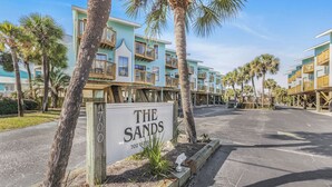 Um hotel à beira-mar com edifícios de vários andares, uma placa com a inscrição 'The Sands 700 West Beach Ave.' e um estacionamento.