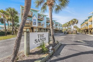 Ein Hotel direkt am Strand mit mehrstöckigen Gebäuden, einer Beschilderung mit dem Schriftzug 'The Sands 700 West Beach Ave.' und einem Parkplatz.