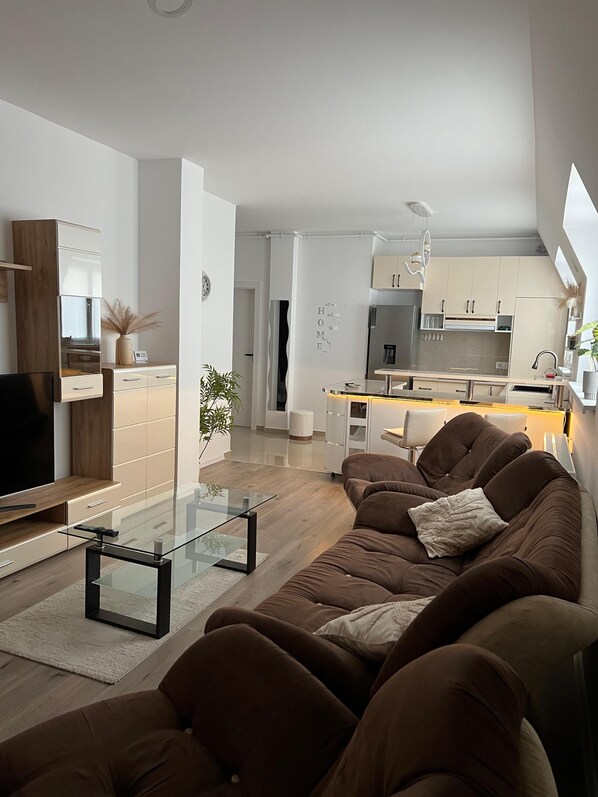 A modern living room with a sofa, TV, and glass coffee table.