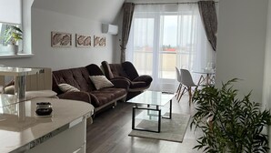 Una sala de estar moderna con un sofá marrón, una mesa de centro de vidrio, un armario blanco y una planta en maceta.