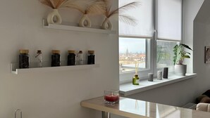 Una cocina moderna con un ventanal grande, encimera blanca y jarrones decorativos en la pared.