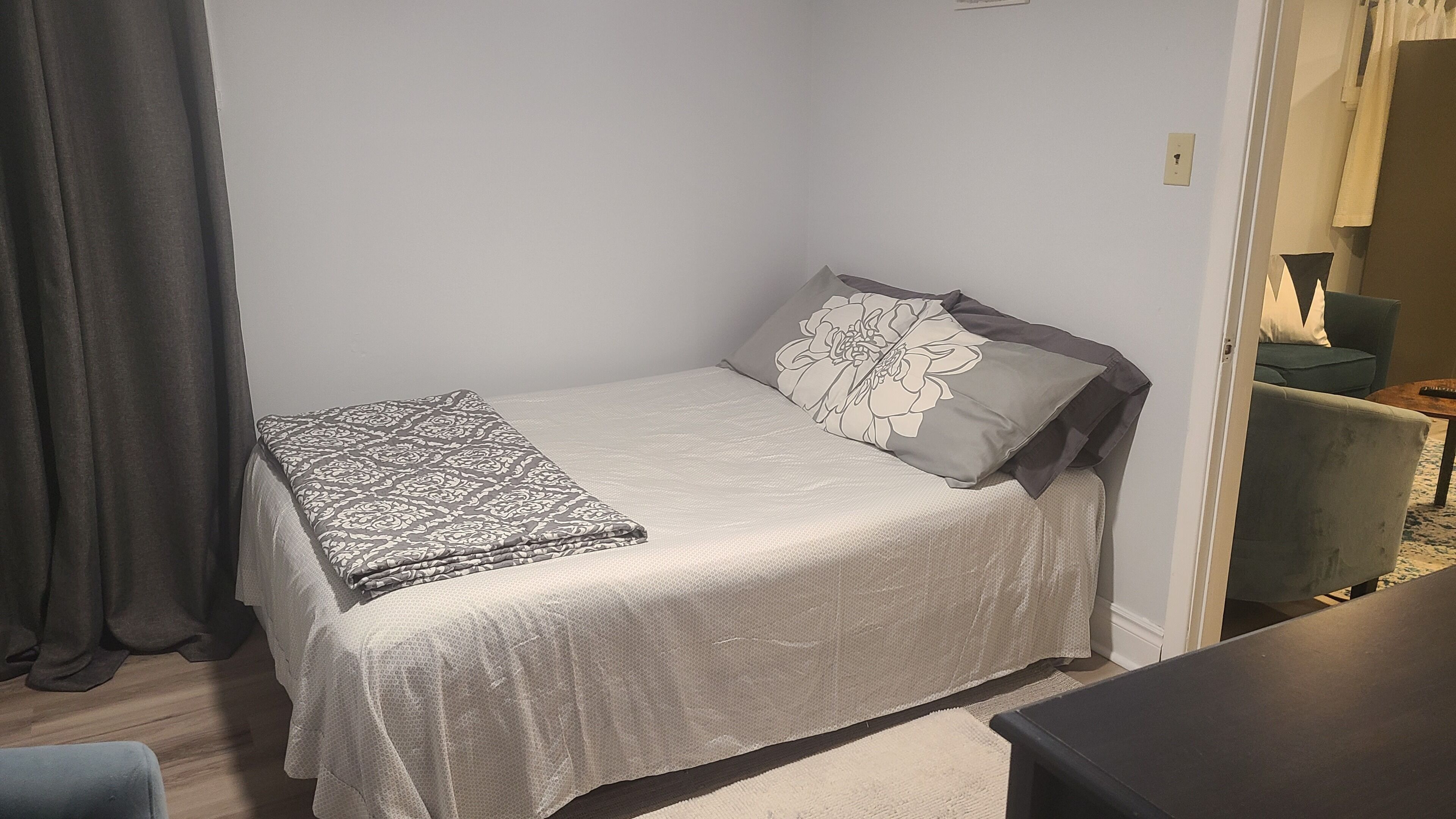 A small, neatly made bed with a patterned blanket and a pillow with a floral design.