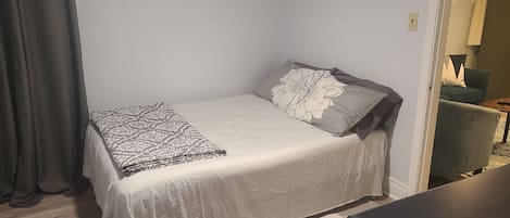 A small, neatly made bed with a patterned blanket and a pillow with a floral design.