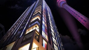 Un immeuble de grande hauteur, avec des fenêtres illuminées et une tour imposante en arrière-plan.