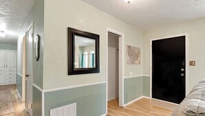 Una habitación con piso de madera, una puerta, un espejo y un mapa en la pared.