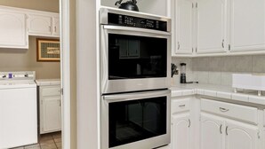 Una cocina con gabinetes blancos, un horno doble y un microondas.