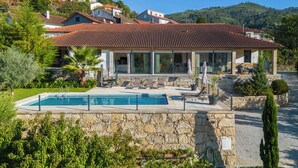 Une villa dotée d’une piscine, d’un espace extérieur aménagé et d’un mur en pierre.