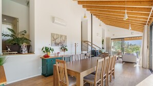 Un espace de repas moderne avec une table et des chaises en bois, un escalier et une vue sur l’extérieur.