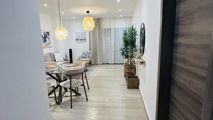 Un interno moderno con zona pranzo, divano, un grande specchio e una pianta in vaso.