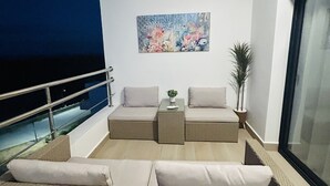 Un balcone con un divano, un tavolino con una pianta e un quadro appeso al muro.