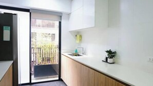 A modern kitchen with a sliding door leading to a balcony, a sink, and a small potted plant. - Apartamento Moderno em Edifício de Luxo - 3 beds/3 baths (Miraflores)