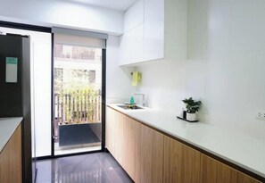 Eine moderne Küche mit einer Schiebetür, die auf einen Balkon führt, einem Spülbecken und einem kleinen Topfpflanzen.