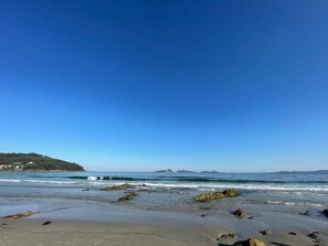 A beach with clear skies, calm water, and distant landforms. - hostal montevideo (Nigrán)