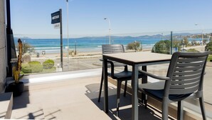 Un balcon avec une table et des chaises, donnant sur une plage et l’océan.