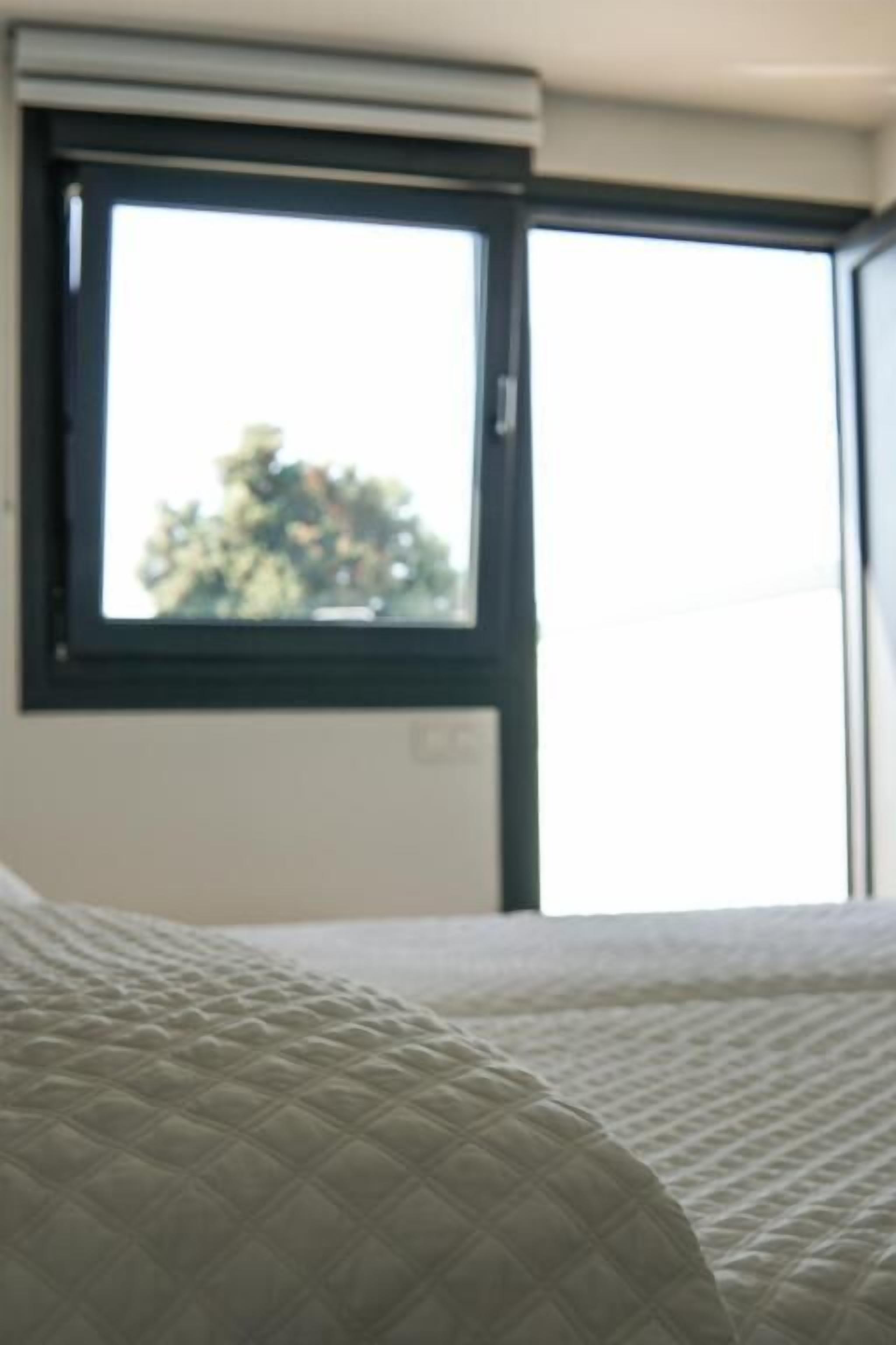 A room with a bed, a window, and a thermostat.