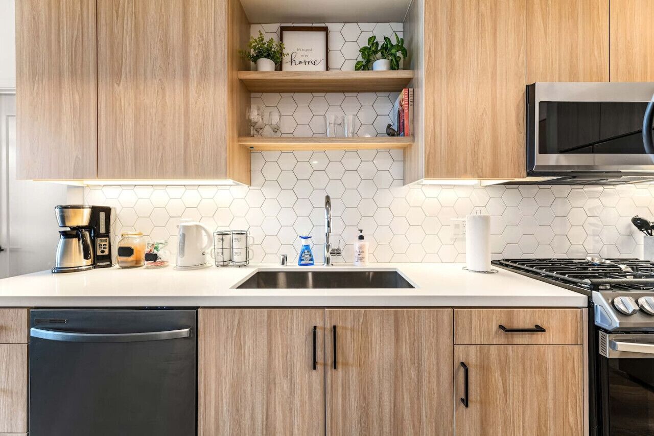 Una cucina con mobili in legno, un lavello in acciaio inossidabile, un forno a microonde, un fornello e una macchina da caffè.