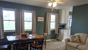 A dining area with a wooden table and chairs, a kitchen with white cabinets, and a ceiling fan. - Spacious home with handicap ramp, boat parking,  a golf cart is also available (Sandusky)