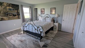 A bedroom with a bed, nightstands, a lamp, a door, and a painting on the wall. - Spacious home with handicap ramp, boat parking,  a golf cart is also available (Sandusky)