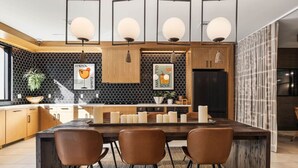 Une cuisine moderne dotée d’un îlot central, de luminaires suspendus et d’un revêtement mural noir et blanc.