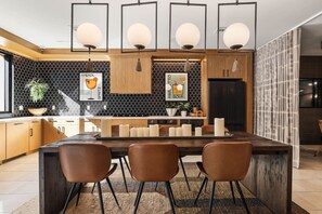 A modern kitchen with a central island, pendant lighting, and a black and white backsplash.