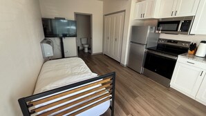 A compact hotel room with a bed, kitchenette, TV, and a bathroom. - Comfortable New Studio in Rawlins Wyoming #3B (Rawlins)