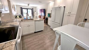 Een moderne keuken met witte kasten, een marmeren aanrechtblad en een vaatwasser.