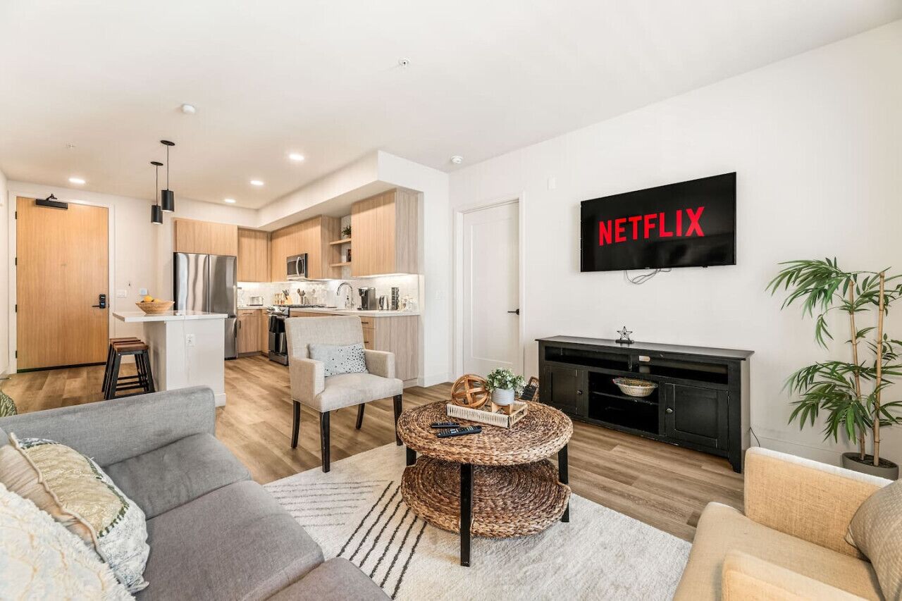 Una sala de estar moderna con un sofá, una mesa de centro y un televisor montado en la pared.