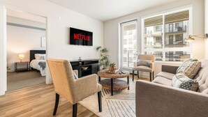 Un salon moderne avec un téléviseur à écran plat, un canapé, un fauteuil et une table basse.