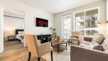 A modern living room with a flat-screen TV, a sofa, a chair, and a coffee table.