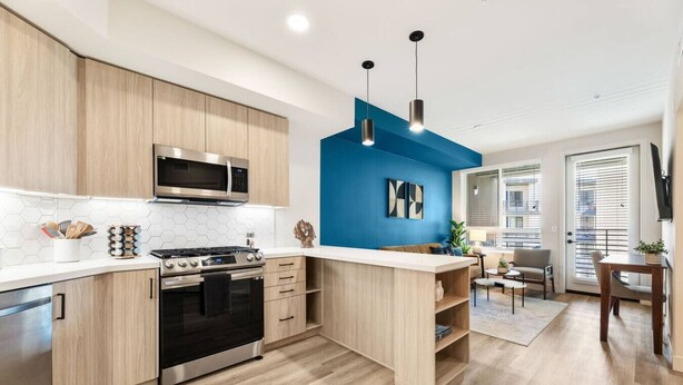 Una cocina moderna con armarios de madera, estufa de acero inoxidable y una pared decorativa azul.