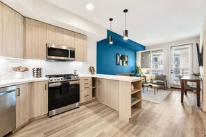 Une cuisine moderne avec des meubles en bois, une cuisinière en acier inoxydable et un mur d’accent bleu.