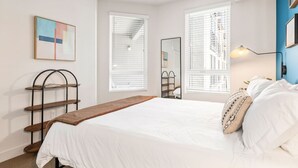 Un dormitorio con cama, mesita de noche, espejo y ventana con persianas.