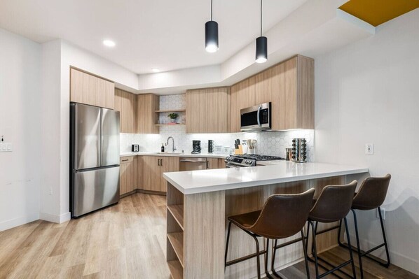 A modern kitchen with a stainless steel refrigerator, a microwave, and a gas stove.