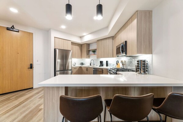 Una cocina moderna con una isla central, electrodomésticos de acero inoxidable y armarios de madera.