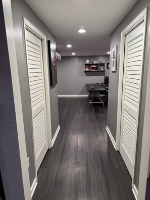 A hallway with a dark wood floor, white doors, and recessed ceiling lights. - Modern 3-bedroom house with park access in Cave Spring (Cave Spring)