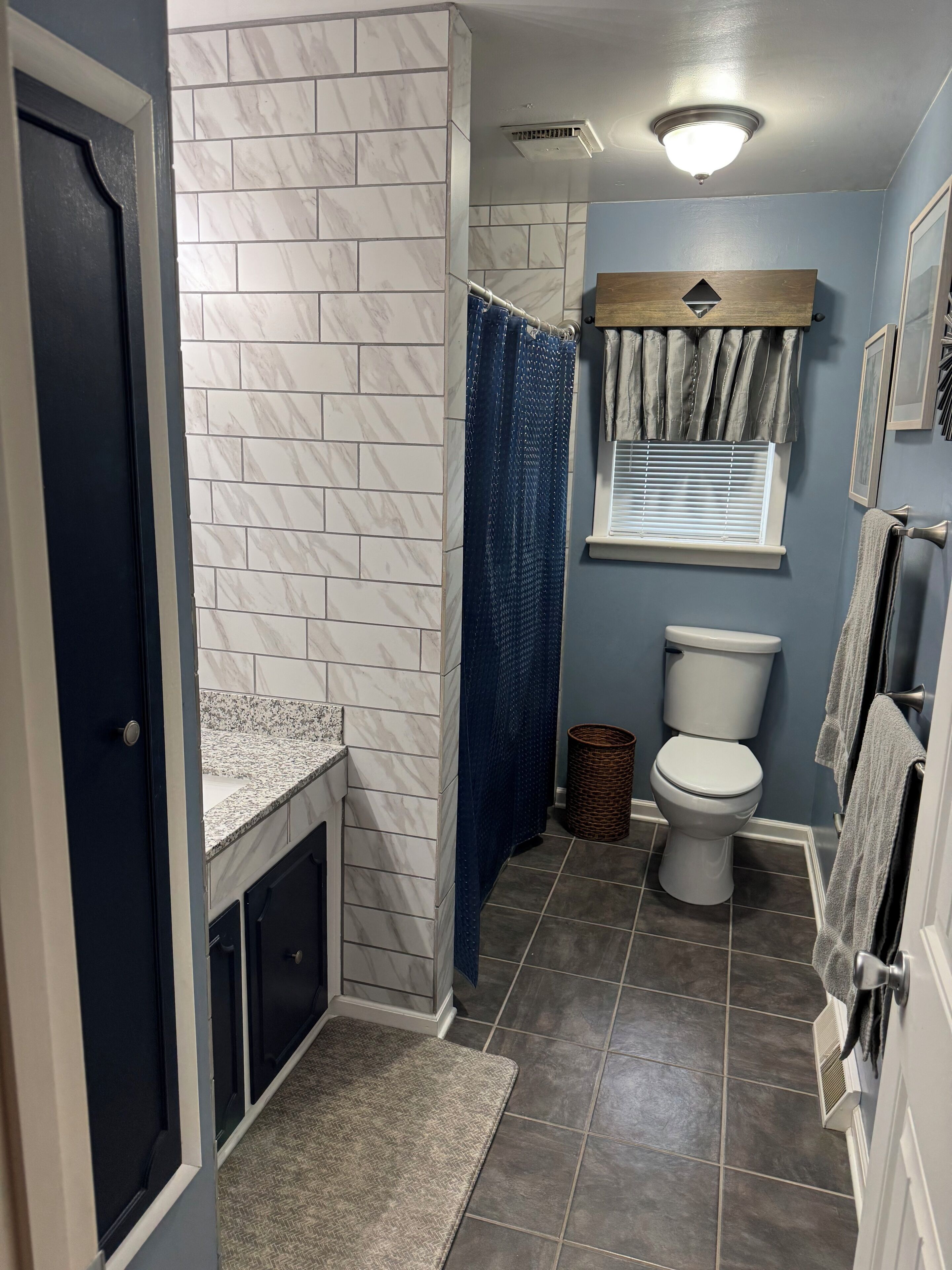 Un baño con inodoro, cortina de ducha y paredes de azulejos.