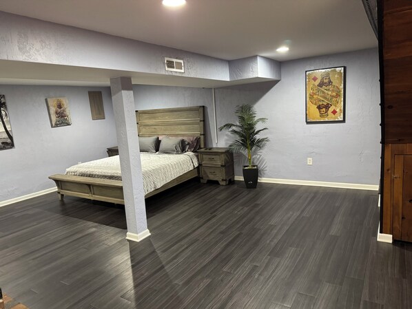 Quarto com cama, mesas de cabeceira, planta em vaso e obras de arte nas paredes.