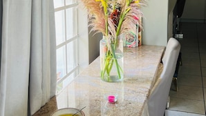 Een keuken met een granieten aanrecht, een vaas met gele bloemen en een wandlamp.